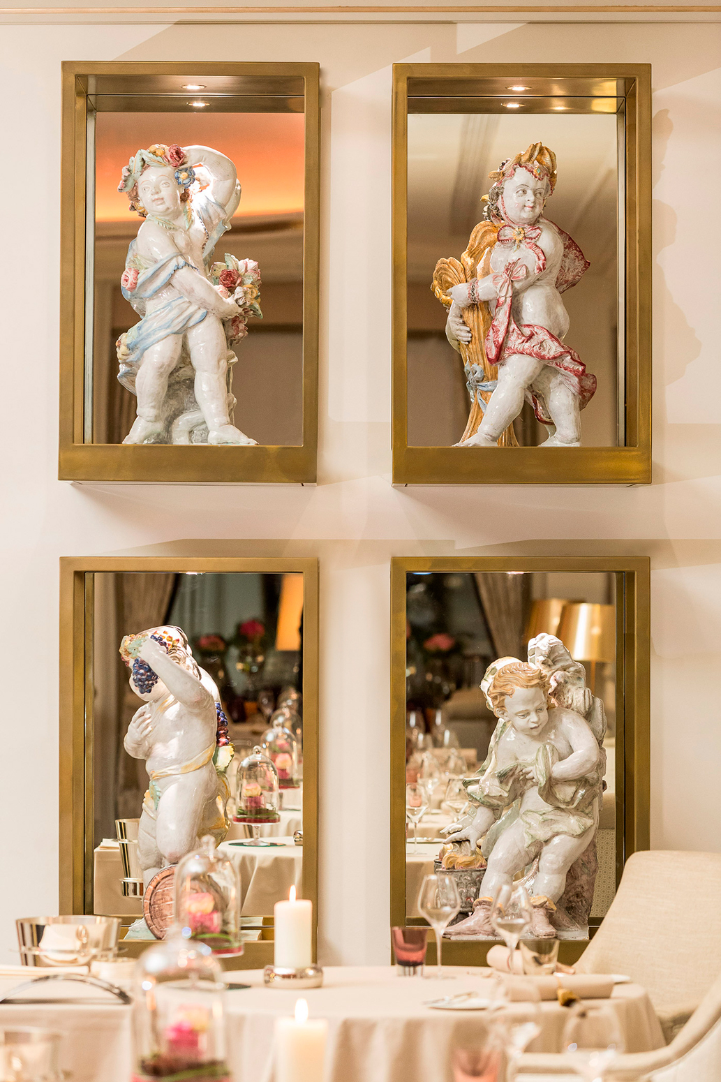 Wand mit verspiegelten Fenstern und kunstvollen Putten aus Porzellan